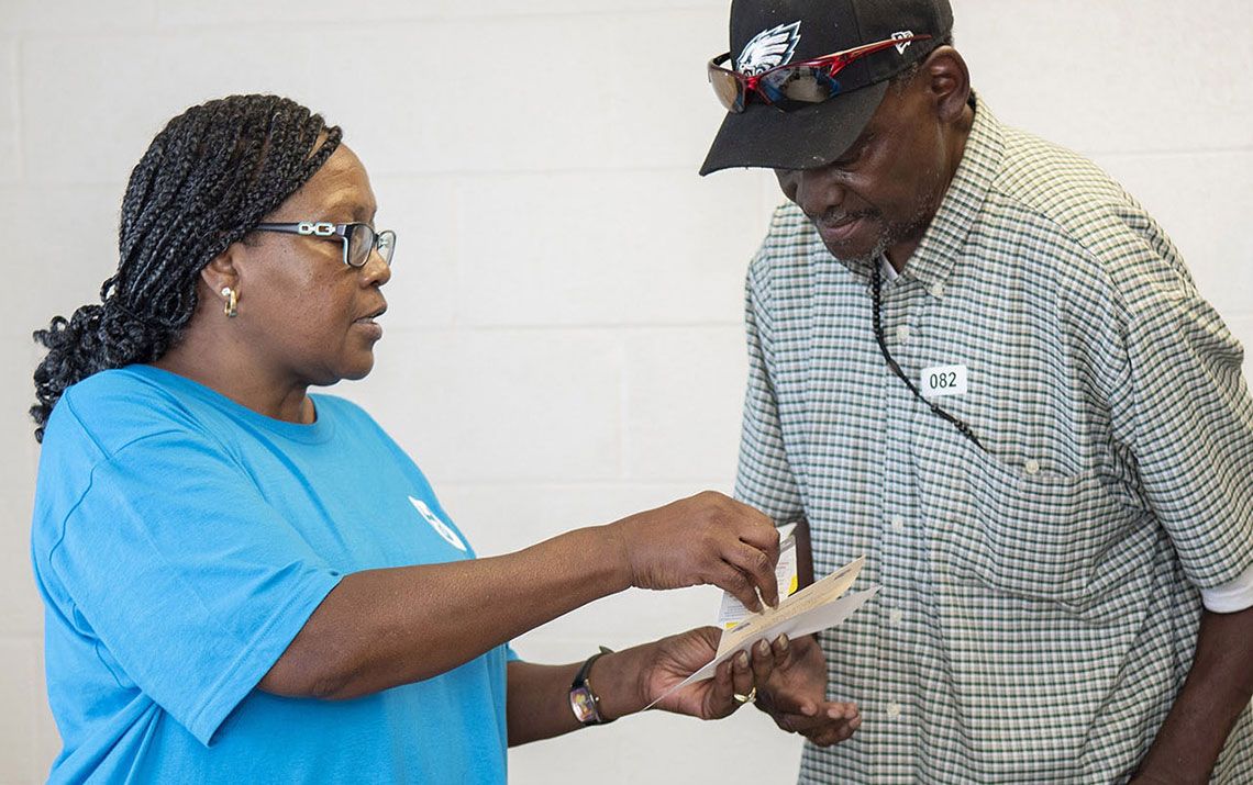 Volunteer helping an elderly participant with their paperwork