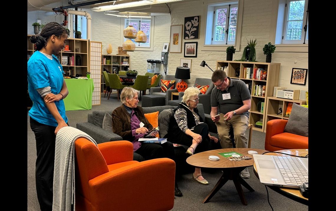 Seated participants talking with HealthDesk volunteers, asking questions about phone skills and digital health 